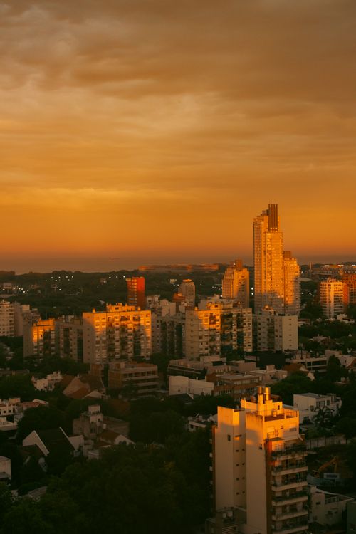 Free Urban skyline at sunset, with buildings bathed in golden light and dramatic sky. Stock Photo