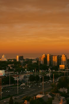 Vibrant sunset casting warm glow over bustling city skyline and buildings.