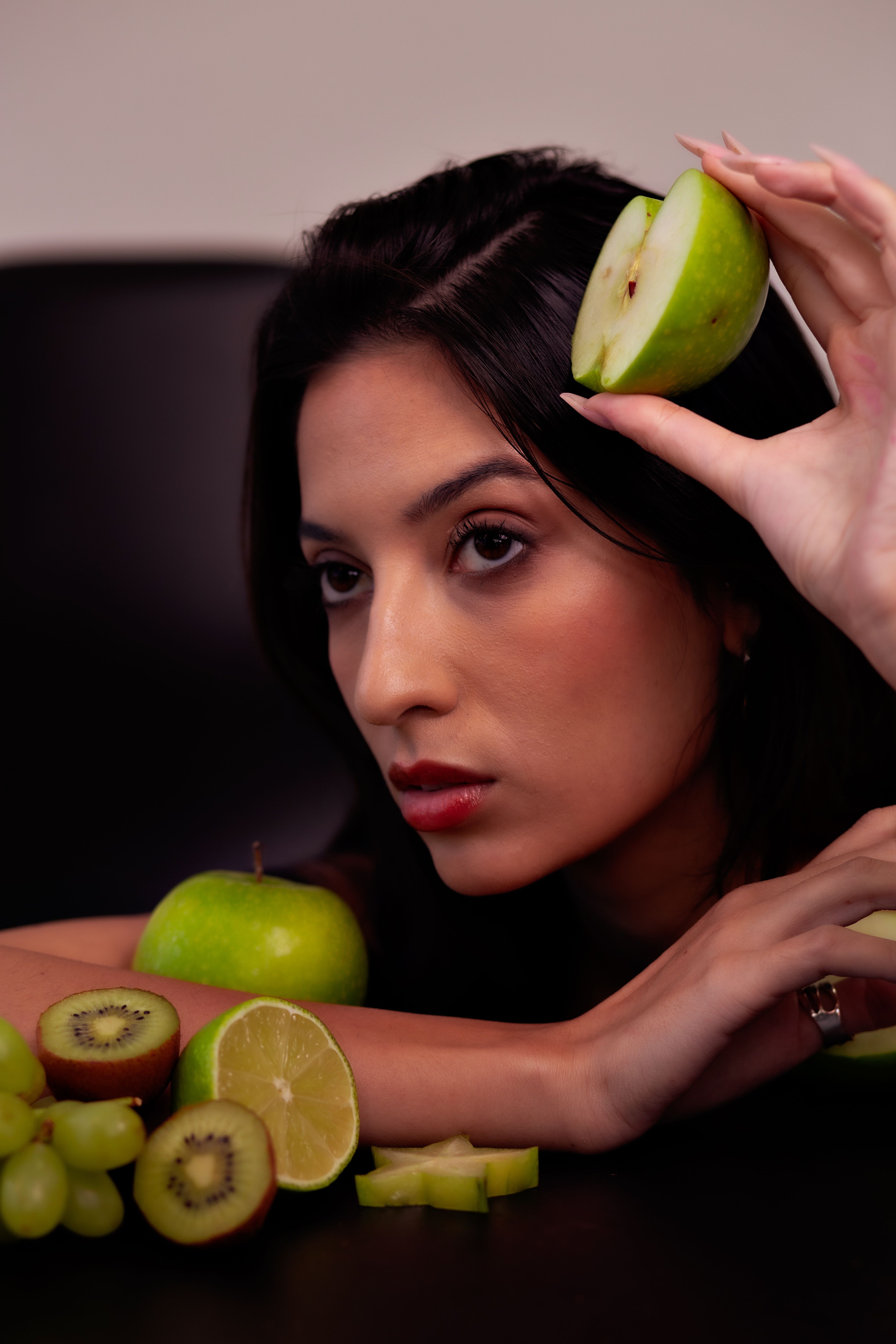 Portrait of a woman posing with apple, kiwi, and grape, showcasing fresh fruits and healthy lifestyle.