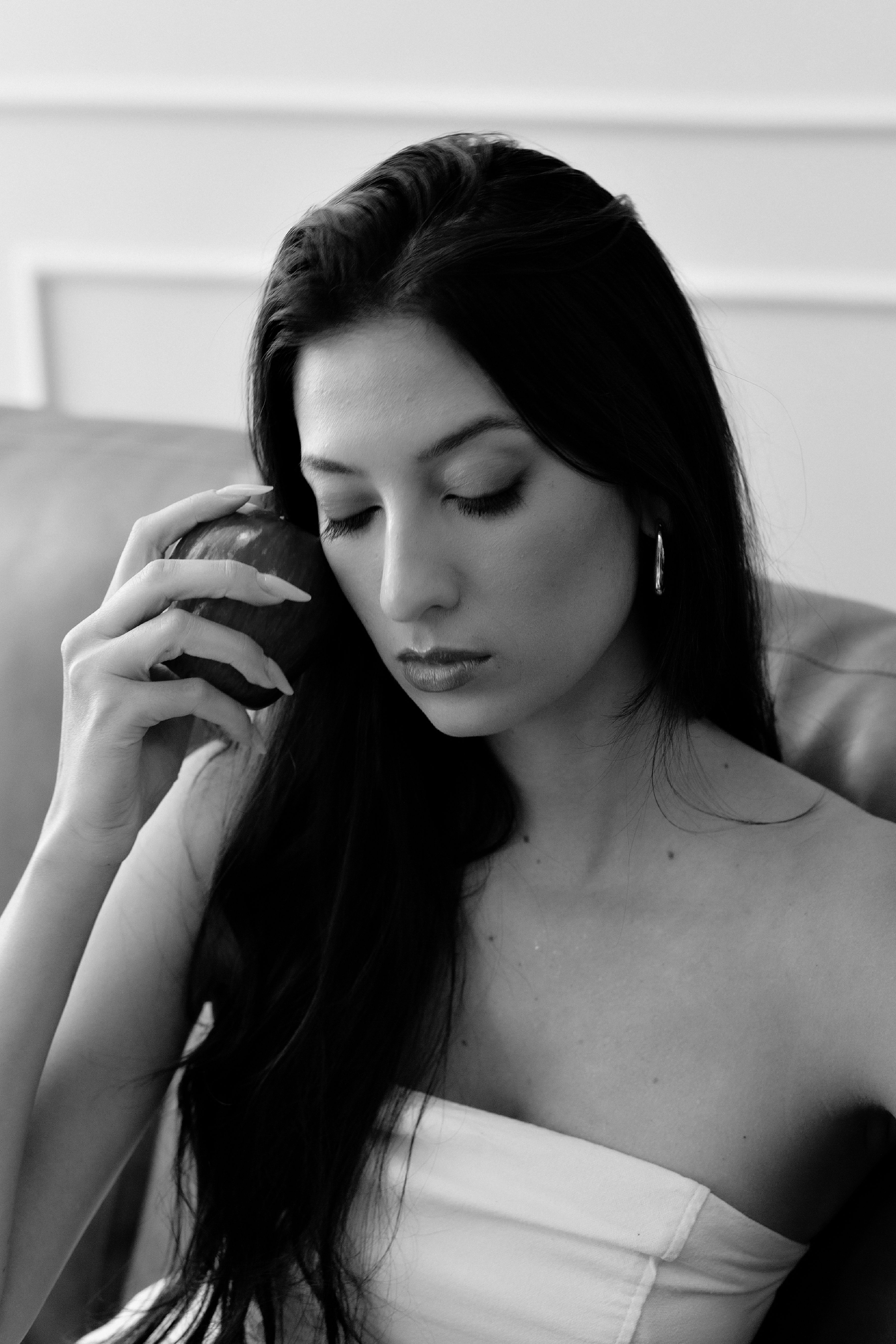 Black and white portrait of a woman holding an apple, exuding elegance and introspection.
