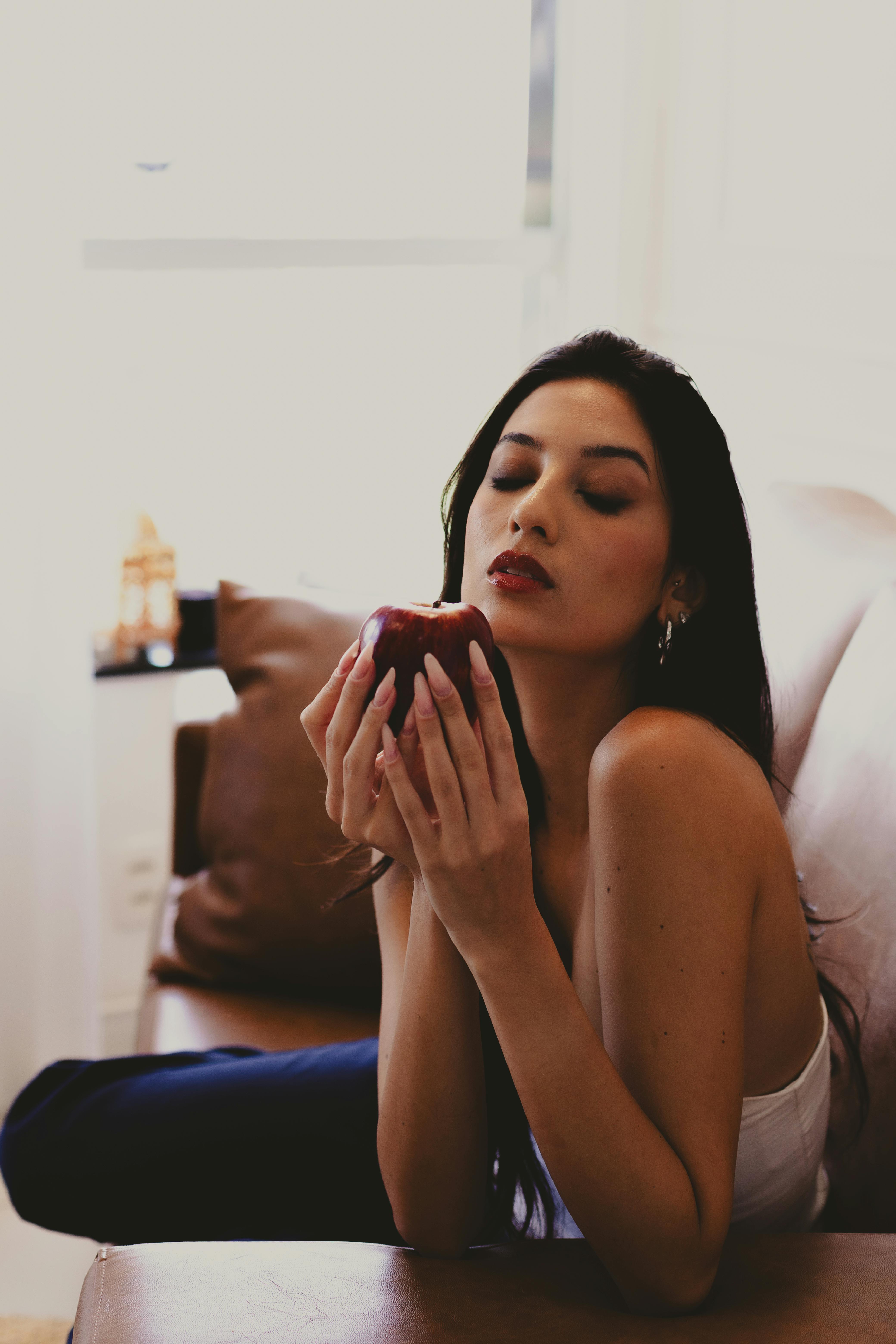 bezplatná Mladá žena uvnitř odpočívá s červeným jablkem, vyzařuje klidnou a hloubavou náladu. Základová fotografie