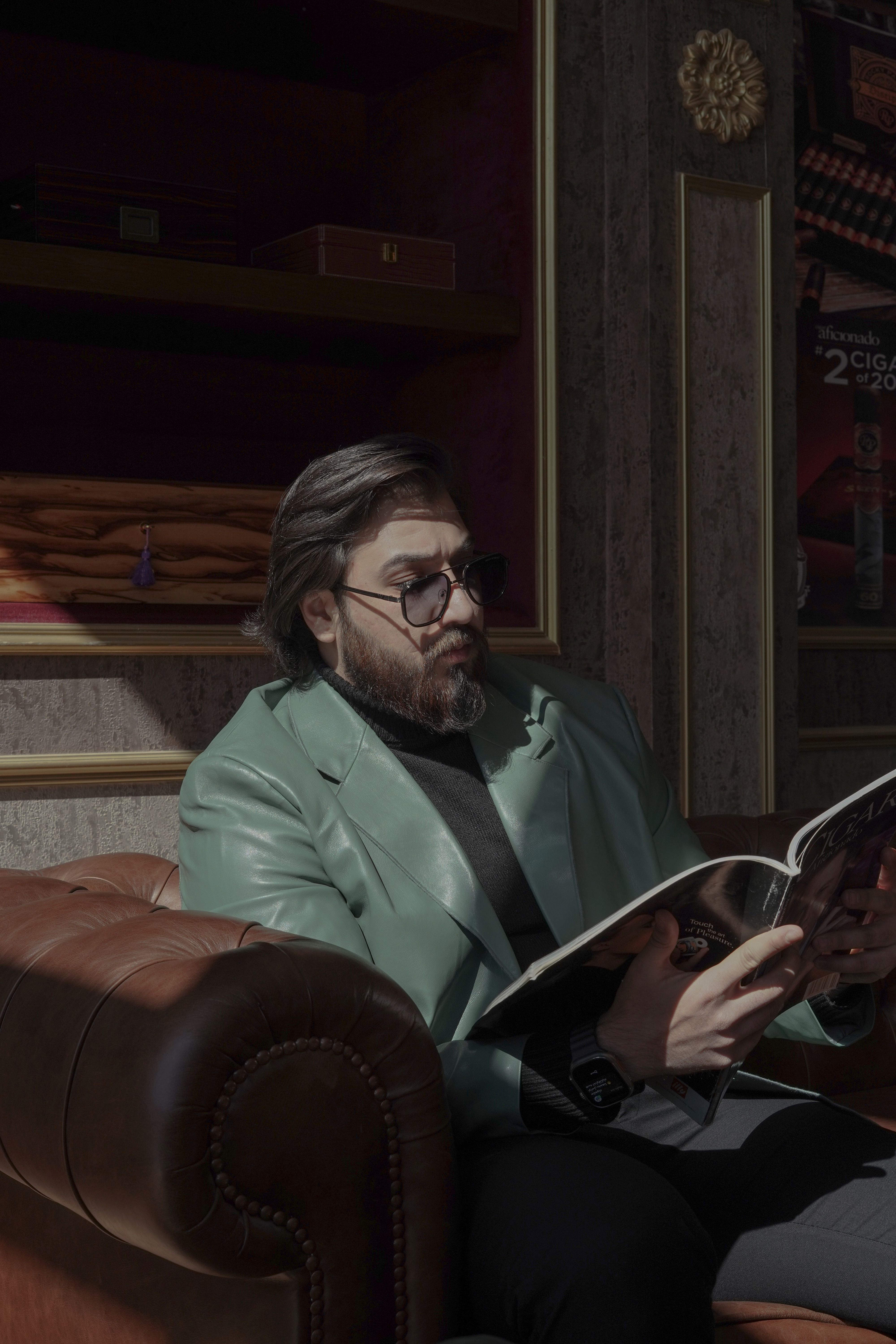 Sophisticated man reading magazine in a dimly lit smoke lounge.