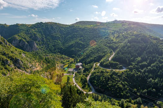 Captivating aerial perspective of a lush green mountain valley under a bright sky.