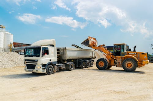 Free Brown Loader Beside White Cargo Truck Stock Photo