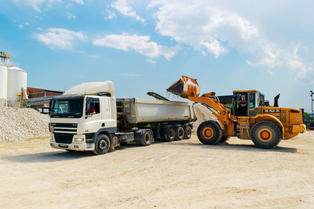Loader placing construction materials onto a cargo truck at a work site