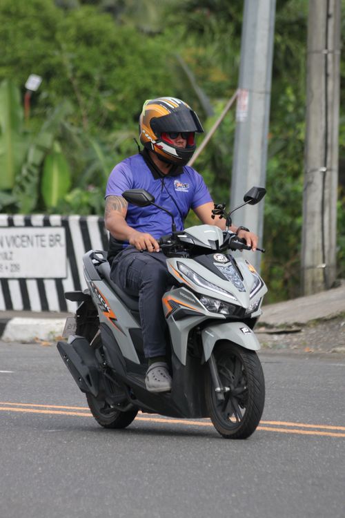 Free A man in protective gear riding a motorcycle on a city street during the day. Stock Photo