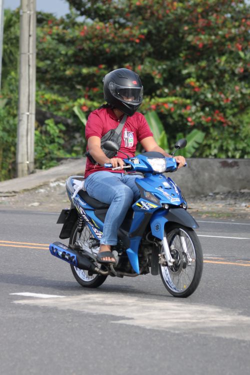 Free A person rides a blue motorcycle on a city street during the day. Stock Photo