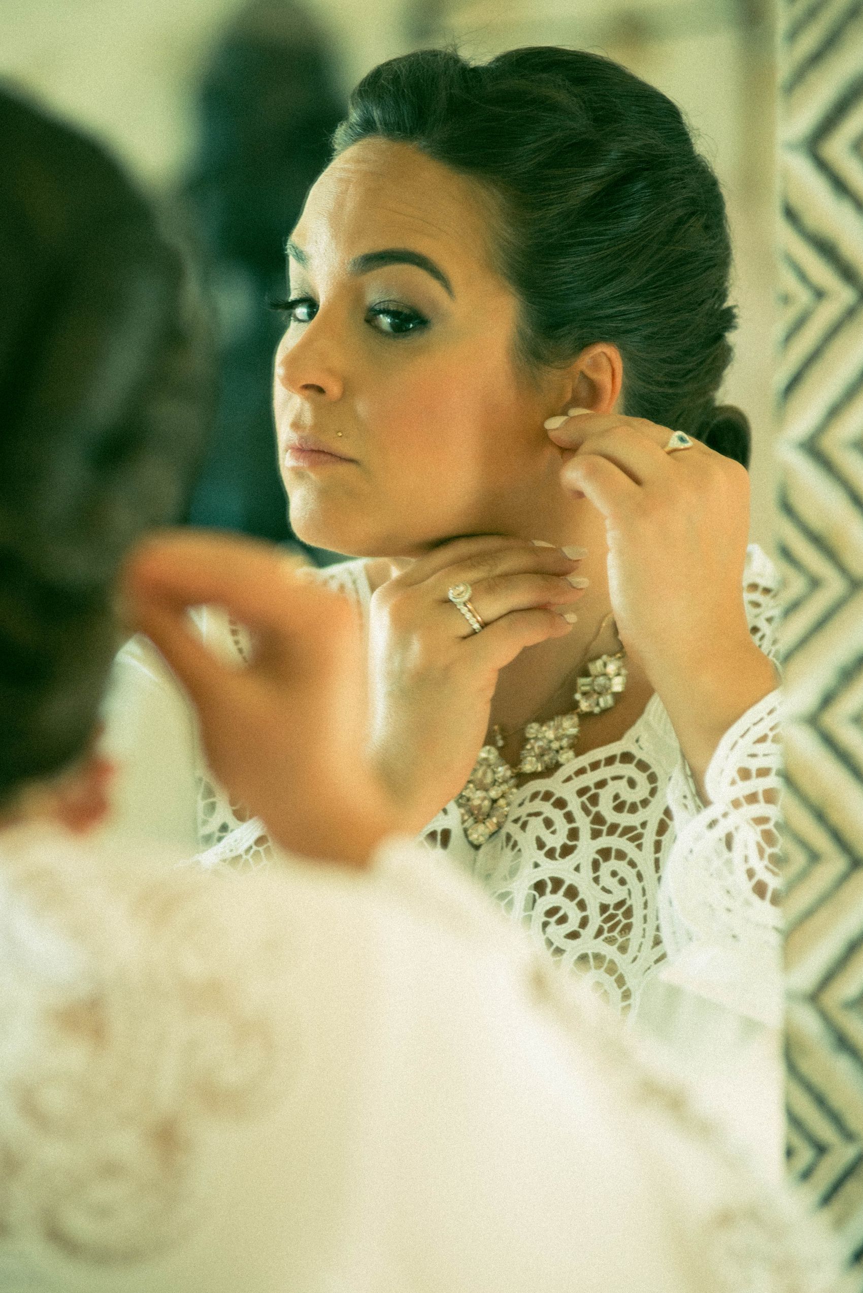 Woman adjusting jewelry in a mirror as part of getting ready
