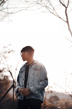 A person in a denim jacket silhouetted against a sunset, exuding tranquility.