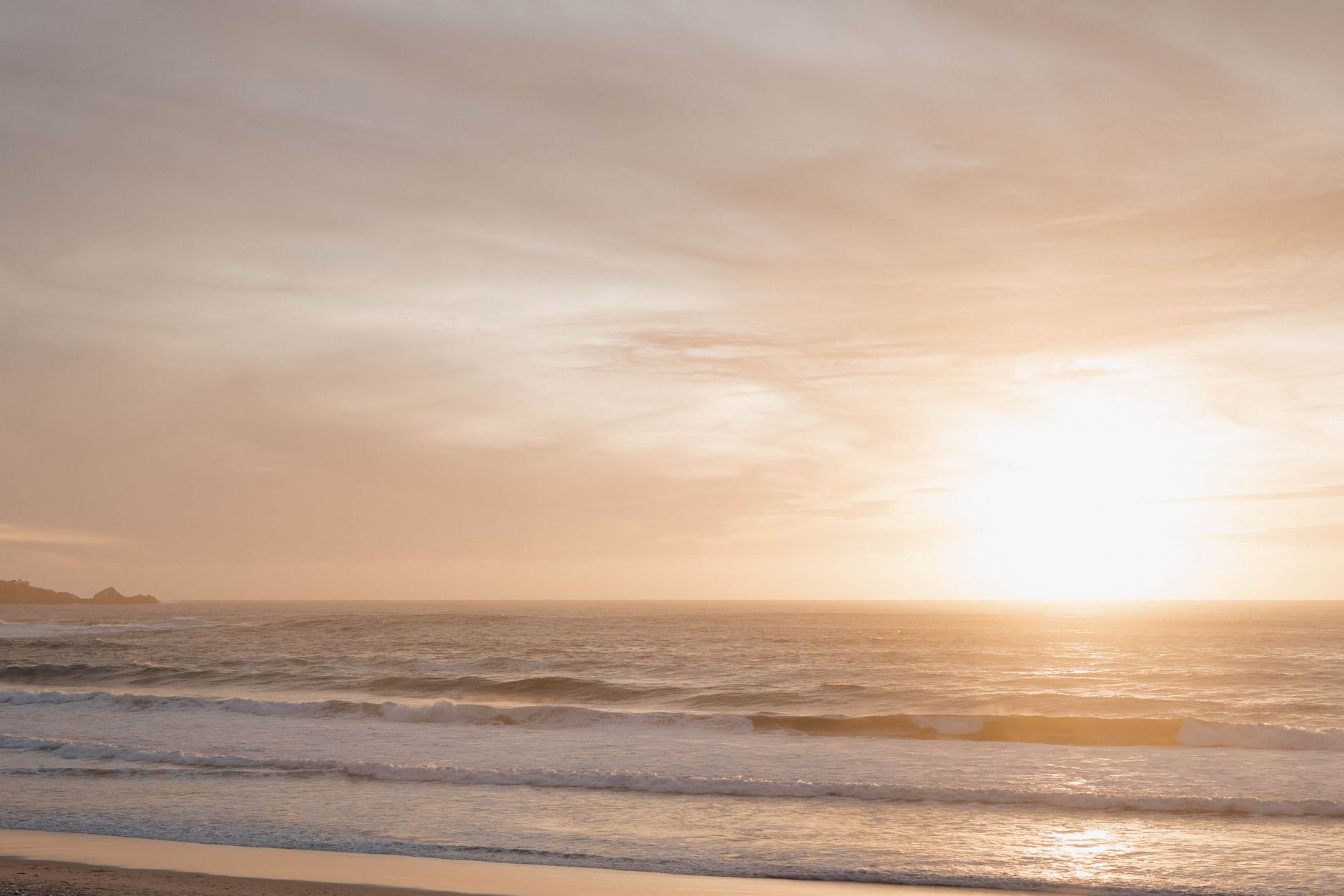 Serene photograph of a golden sunset over ocean waves at Carmel Beach, California.