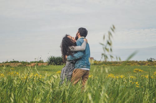 Man and Woman Hugging Each Other on Green Grass Field