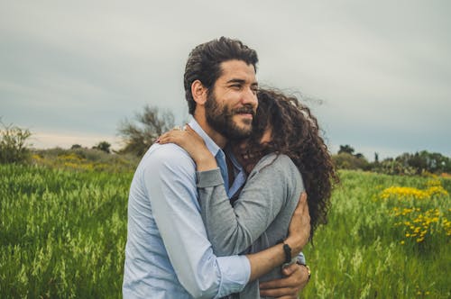 A Happy Couple Hugging Each Other In A Grass Field