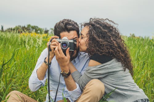 Free Woman Kissing A Man Holding A Camera Stock Photo
