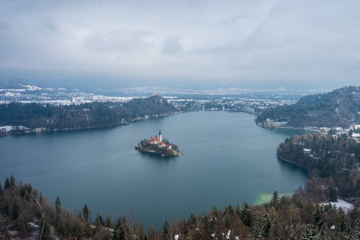 A breathtaking winter view of Lake Bled with its iconic island church amid snowy landscapes.