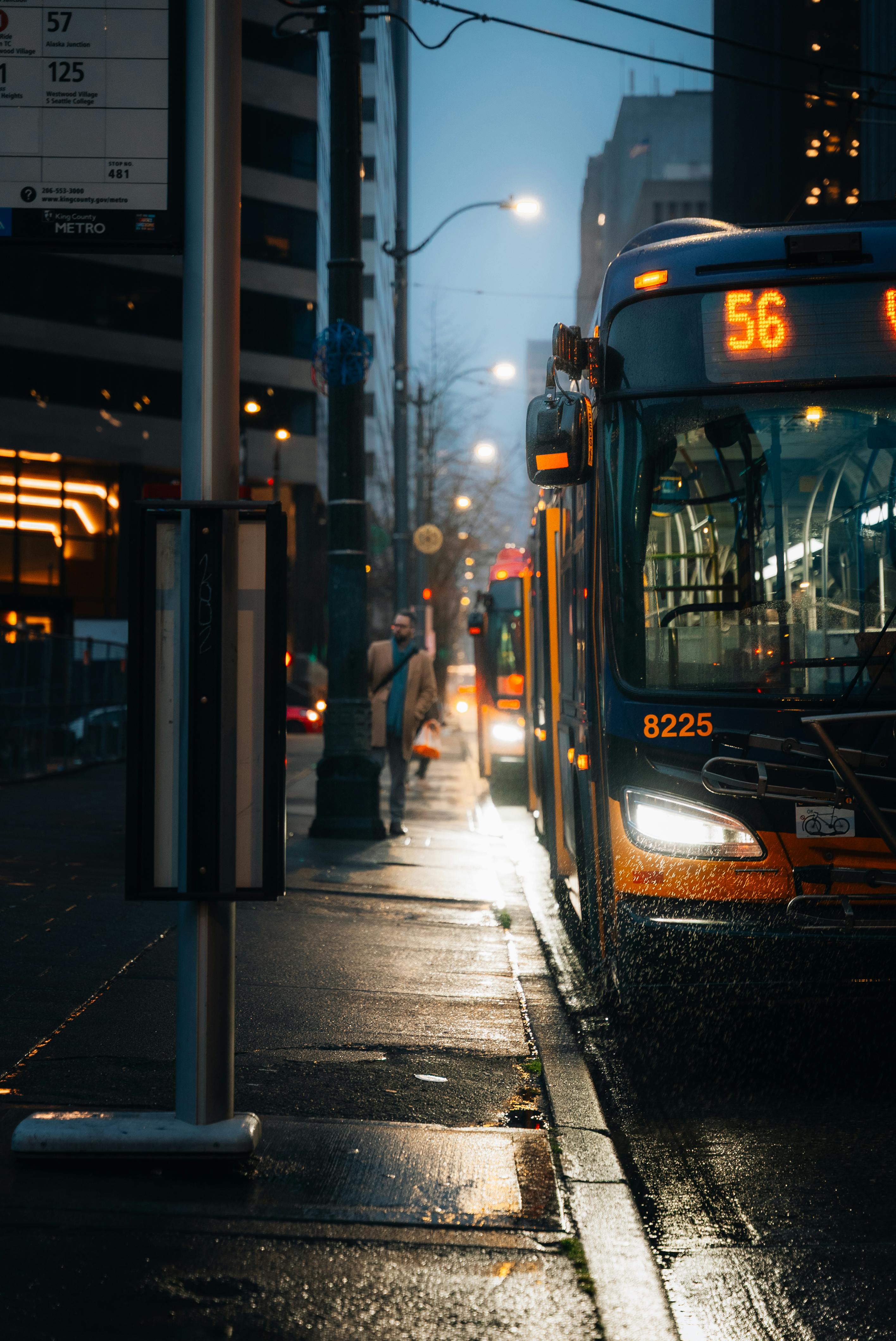 A rainy evening captures the vibrant urban life in downtown Seattle with a city bus in focus.