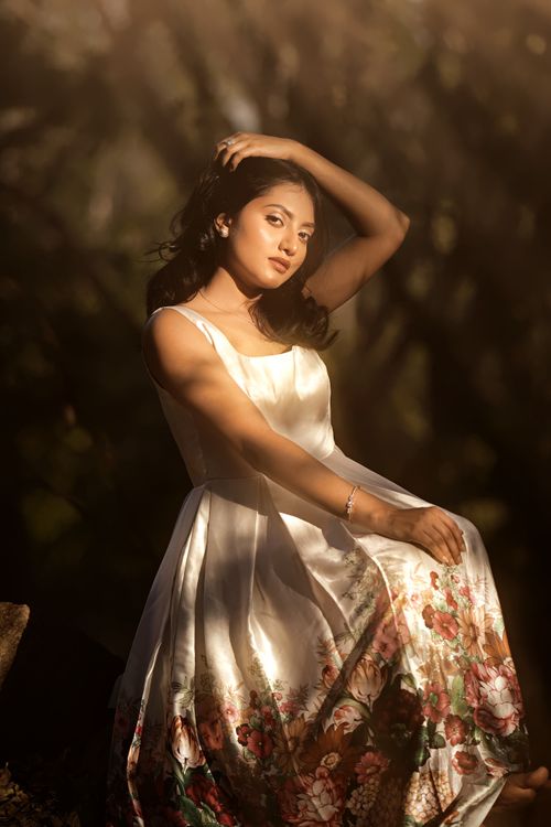 Free Woman in a floral dress poses elegantly in a sunlit forest setting, capturing natural beauty. Stock Photo