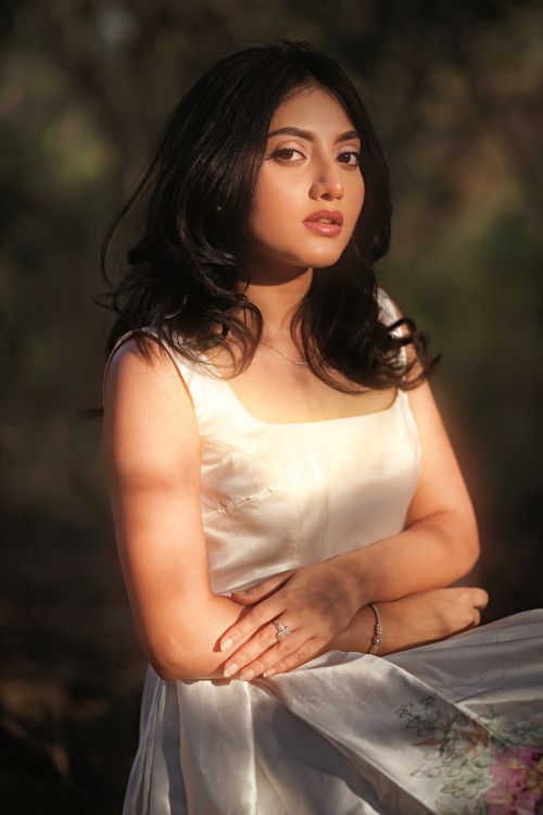 Free A serene portrait of a woman in a white dress, lit by gentle forest sunlight. Stock Photo