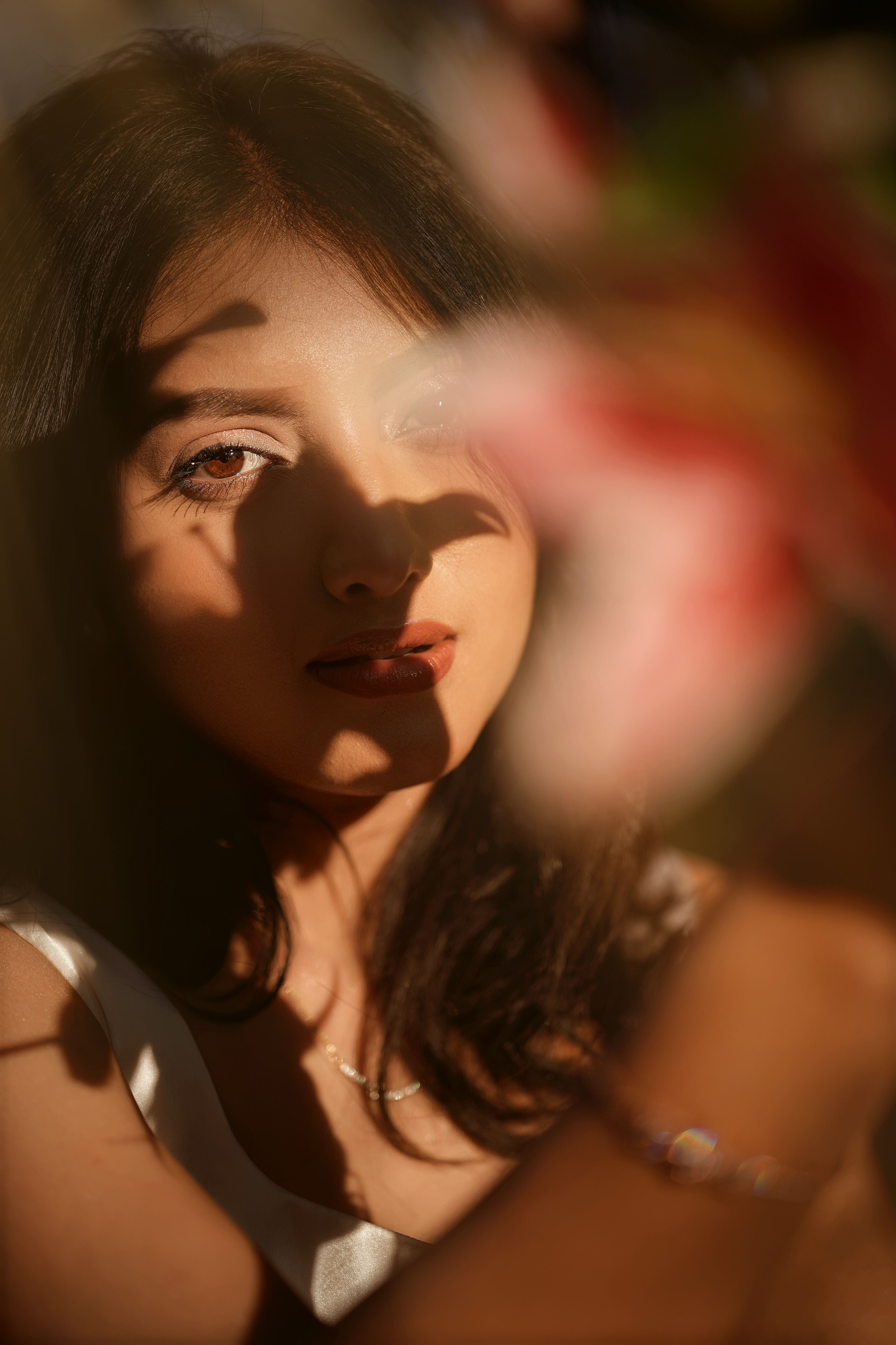 A young woman bathed in dramatic light and shadow creates a mysterious artistic portrait.