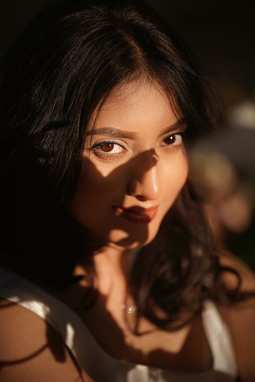 Free A close-up portrait of a woman with artistic lighting and shadows creating a mysterious look. Stock Photo