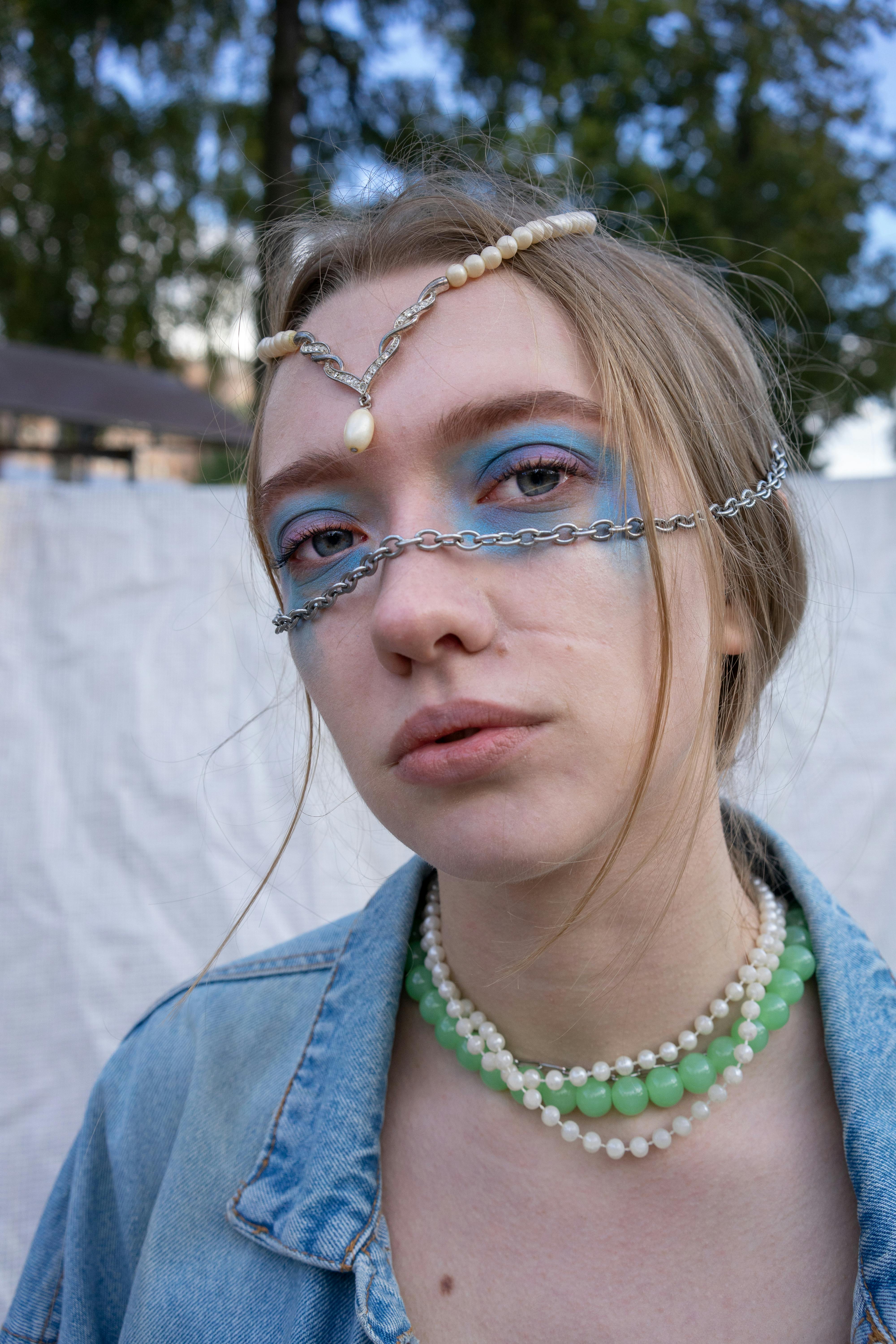 Portrait of a woman wearing creative jewelry and makeup, set outdoors.