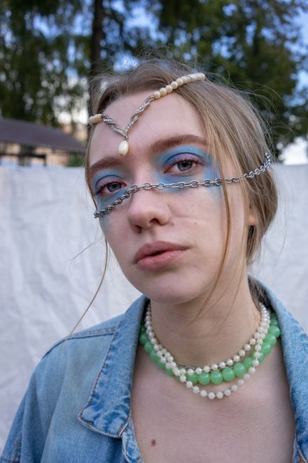 Portrait of a woman wearing creative jewelry and makeup, set outdoors.