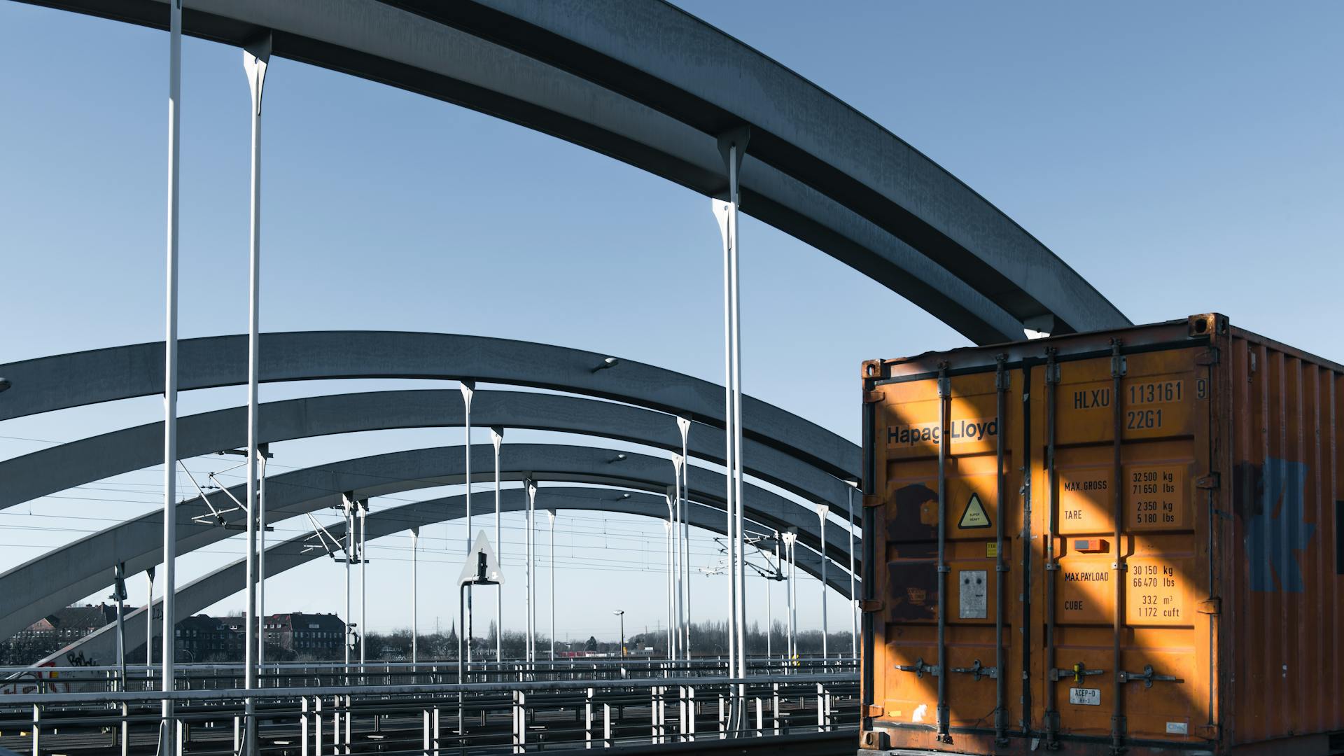 Steel arch bridge with a shipping container under clear skies in Hamburg, Germany.