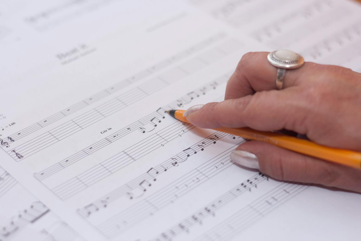 Hand writing music notes on sheet music