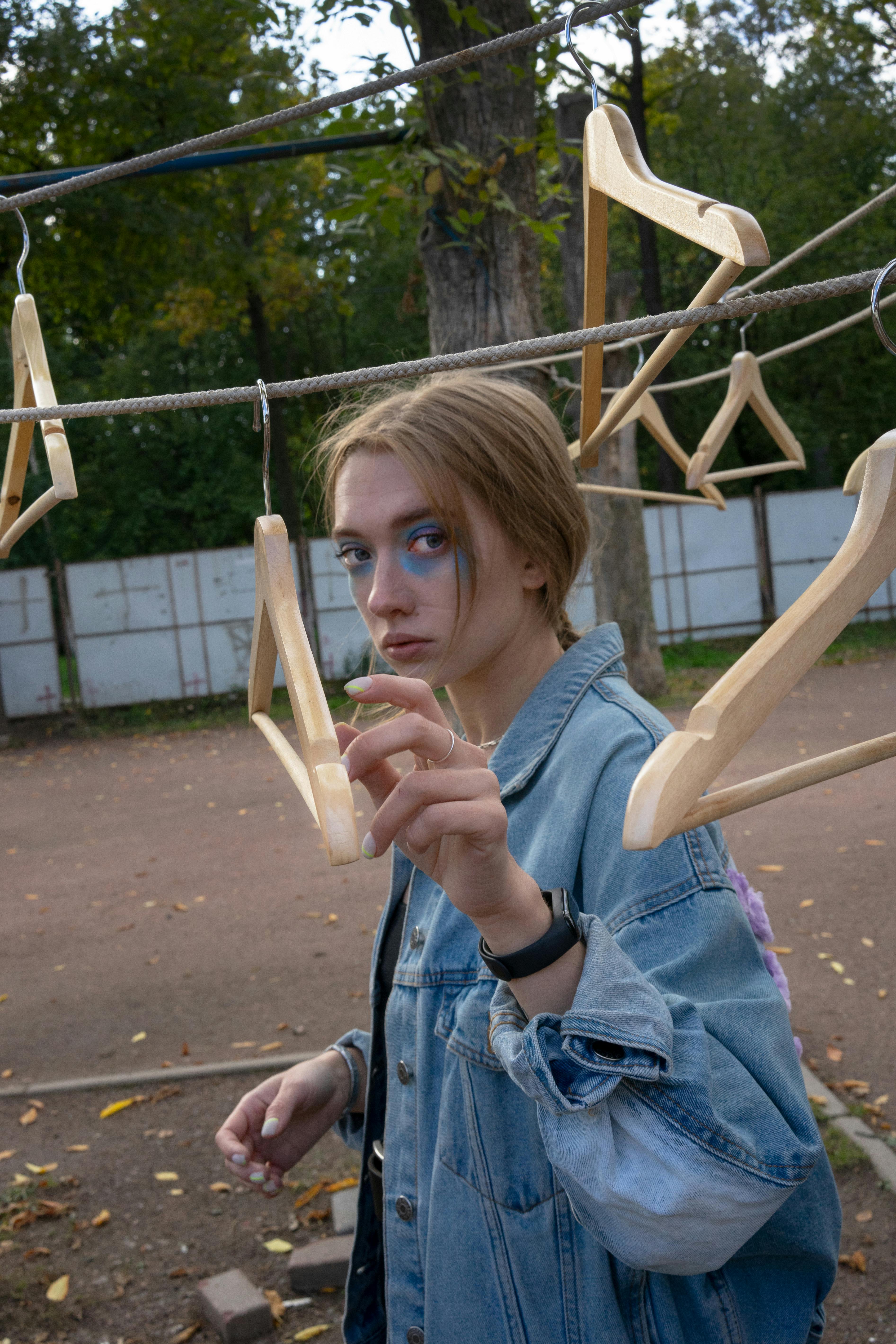 一位年轻女子在户外与木衣架互动，站在一条线上