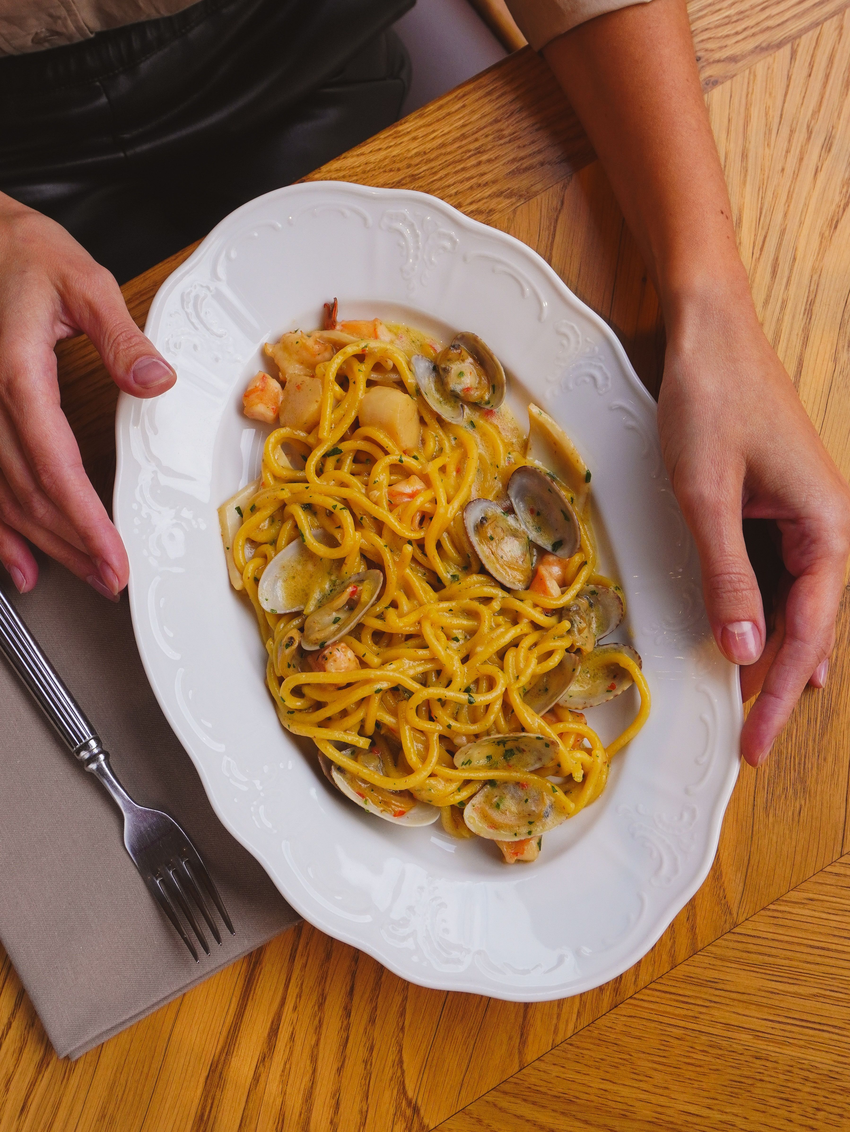 A flavorful seafood pasta dish served on a white ornate plate, ready to enjoy.