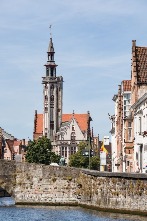 Free Charming view of Bruges architecture with a church tower reflecting in the canal. Stock Photo