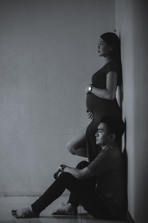 Photographie En Niveaux De Gris De L'homme Et De La Femme S'appuyant Sur Le Mur