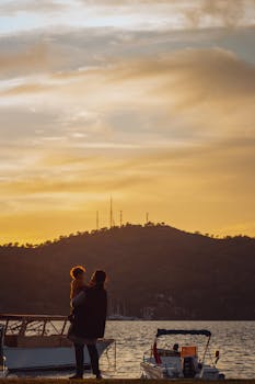 A warm and serene seaside sunset with a parent holding a child, creating a peaceful silhouette against the evening sky.