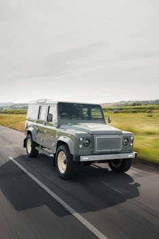 A classic SUV in motion on a scenic country road, highlighting adventure and travel.