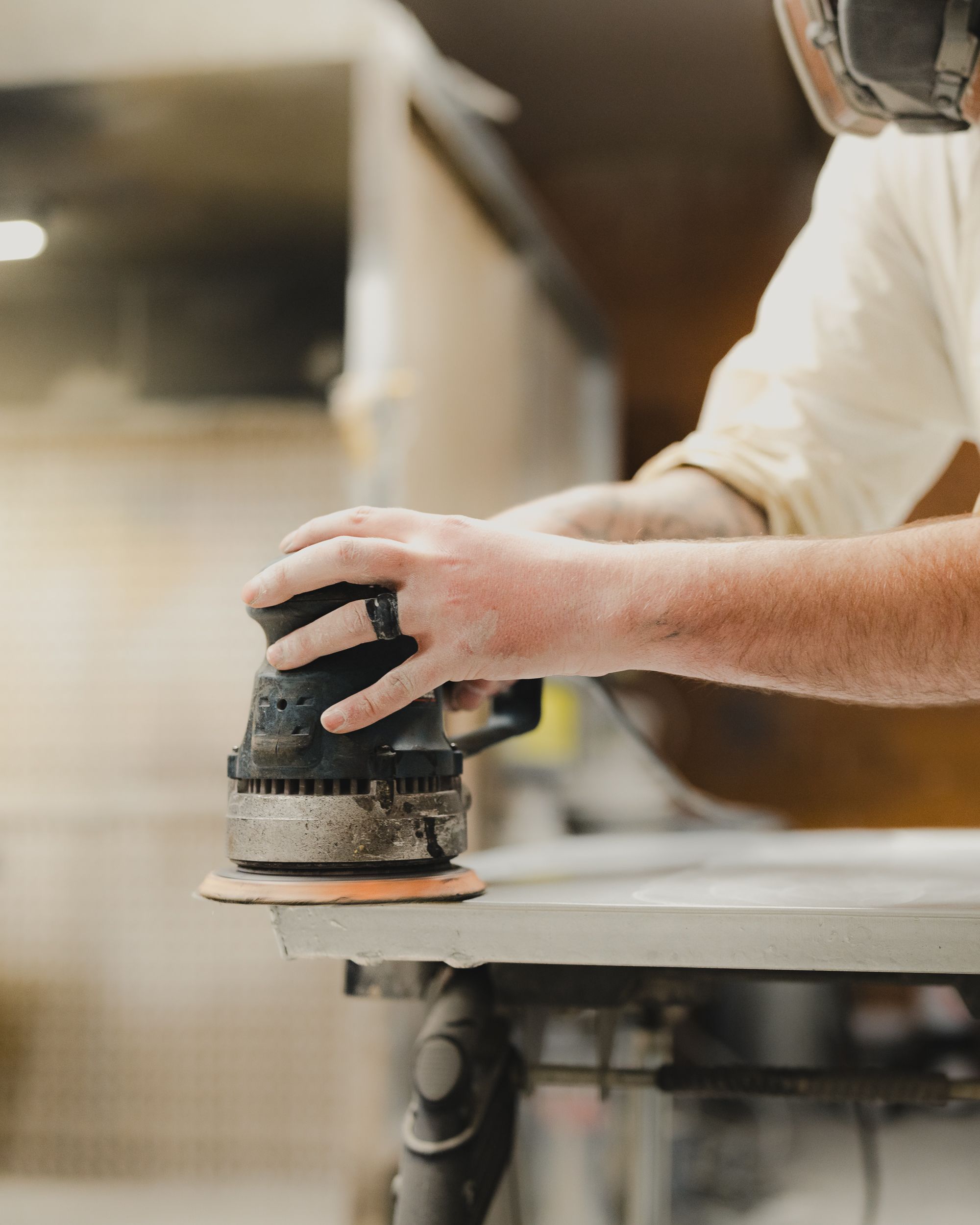 Close-up of a carpenter using an orbital sander on a wooden surface, showcasing craftsmanship.
