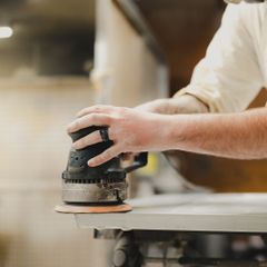 A dark sander smoothing a pale board
