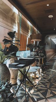 Luxurious restaurant interior featuring lush plants, stylish decor, and geometric floor design.