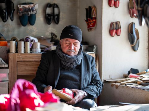 Free An elderly shoemaker in Kahramanmaraş, Türkiye, crafting shoes in his workshop surrounded by materials. Stock Photo