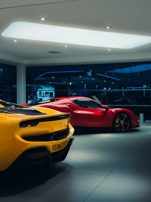 Free Showroom with two luxury sports cars under soft lighting, showcasing sleek design. Stock Photo