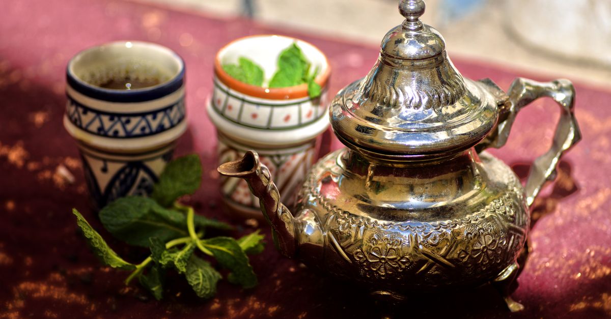 A traditional Moroccan mint tea set with a silver teapot and cups outdoors in Fès, Morocco.