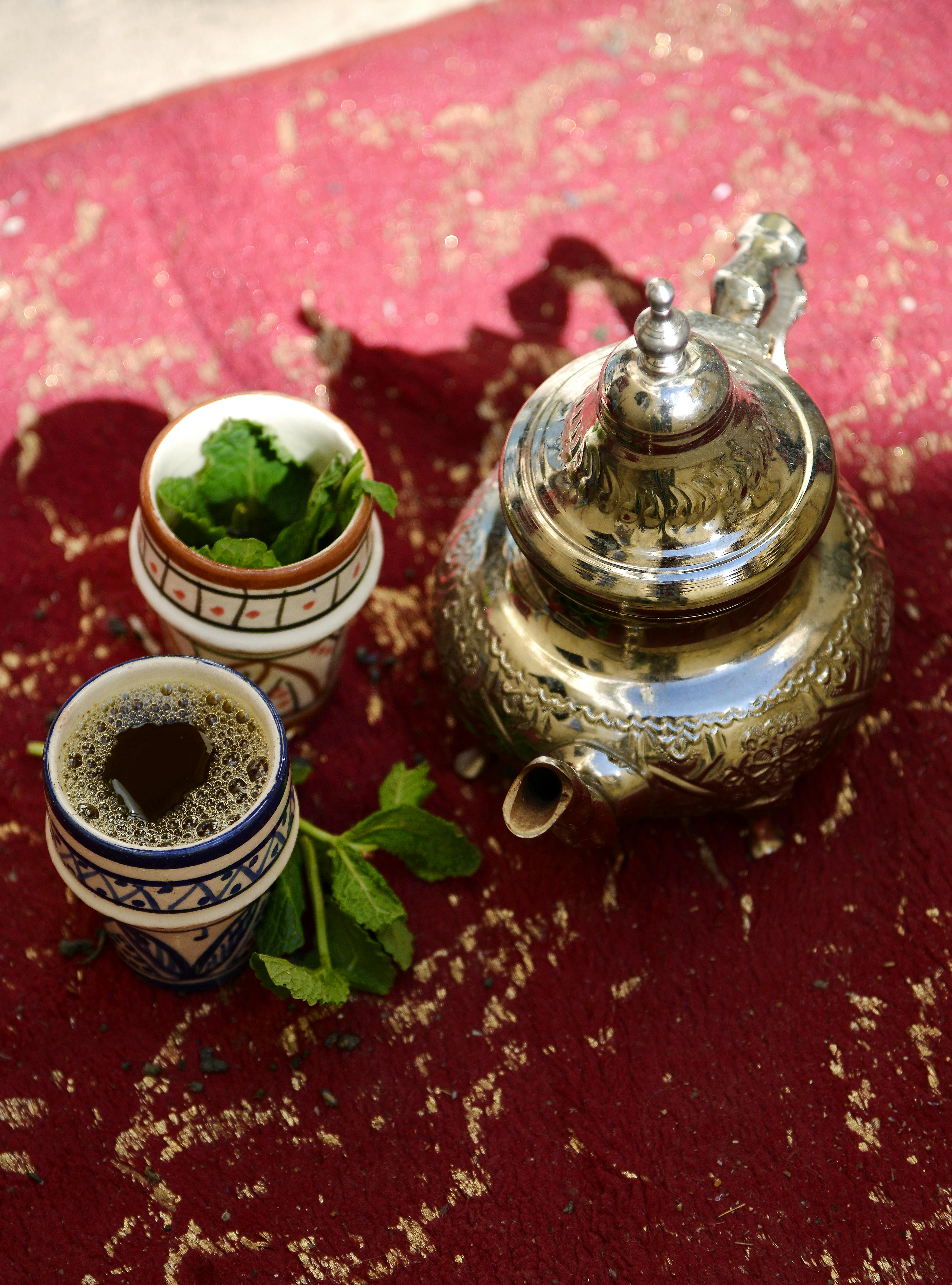 Authentic Moroccan mint tea set with silver teapot and cups on a vibrant red rug, Fès, Morocco.