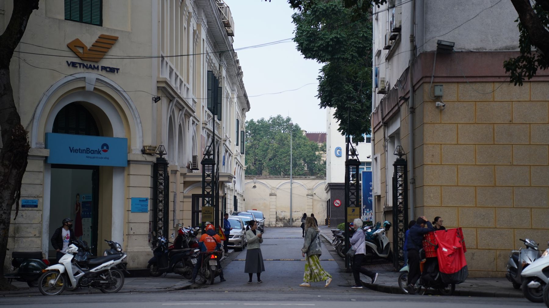 Lebhafte Straßenszene in Hanoi mit Motorrädern und Fußgängern in der Nähe der Vietnam Post und VietinBank.