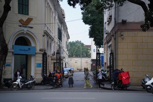 Vibrant street scene in Hanoi with motorbikes and pedestrians near Vietnam Post and VietinBank.