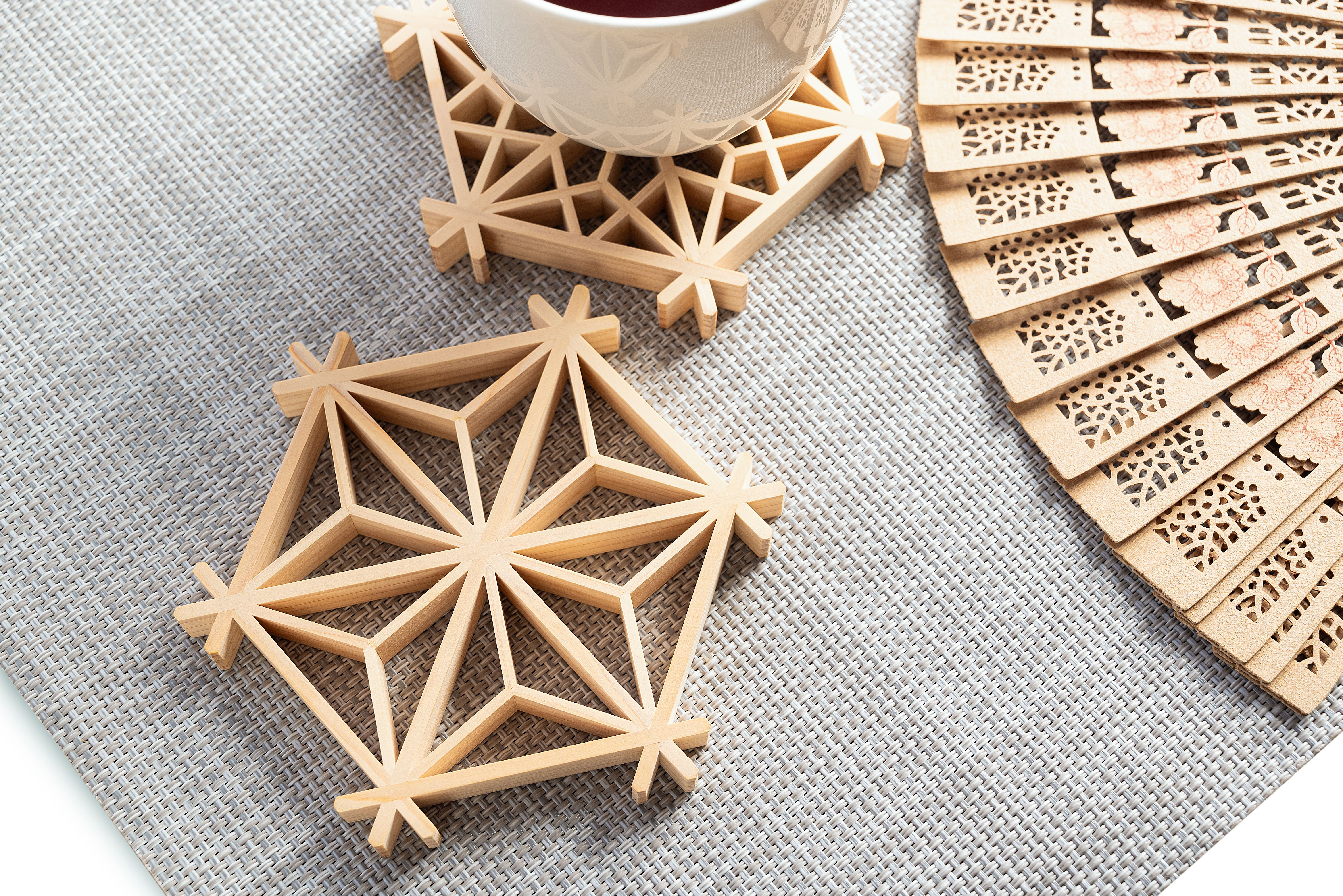 Stylish wooden coasters and traditional fan on a woven mat