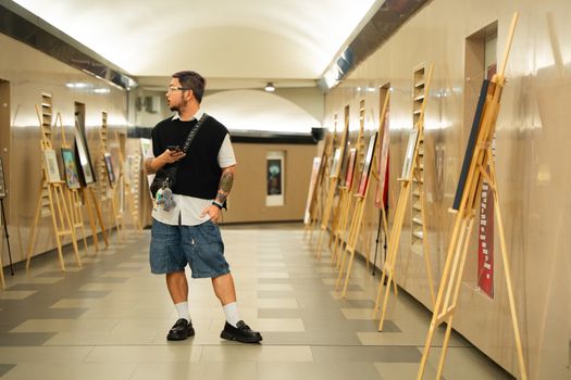 Man appreciating art in a modern gallery, surrounded by artworks and easels.