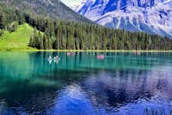 在不列颠哥伦比亚省翡翠湖宁静的水域上，独木舟轻轻滑行，四周环绕着茂密的森林和雄伟的山峰