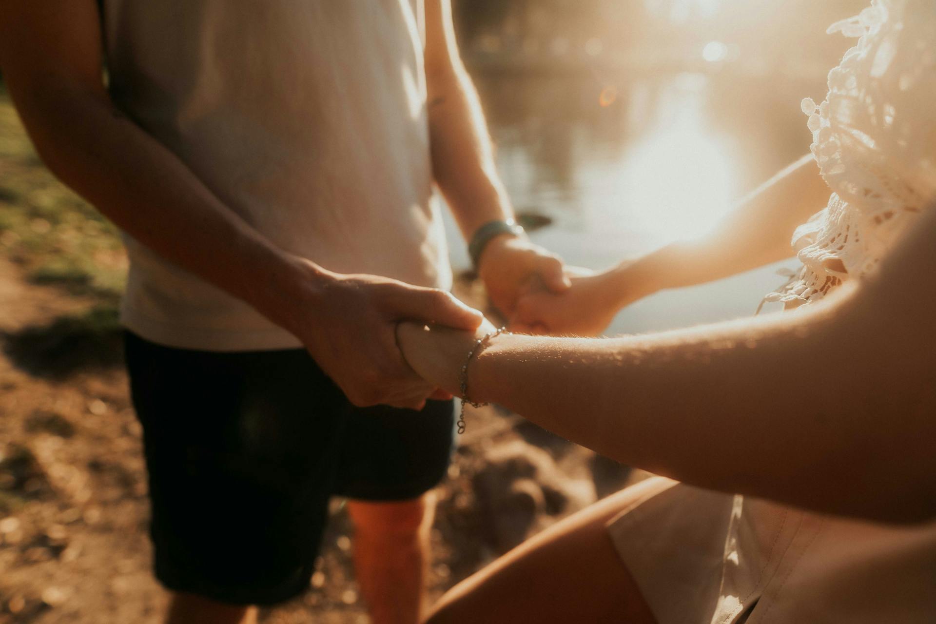 A loving couple holding hands by a serene lake in Buenos Aires, Argentina at sunset.