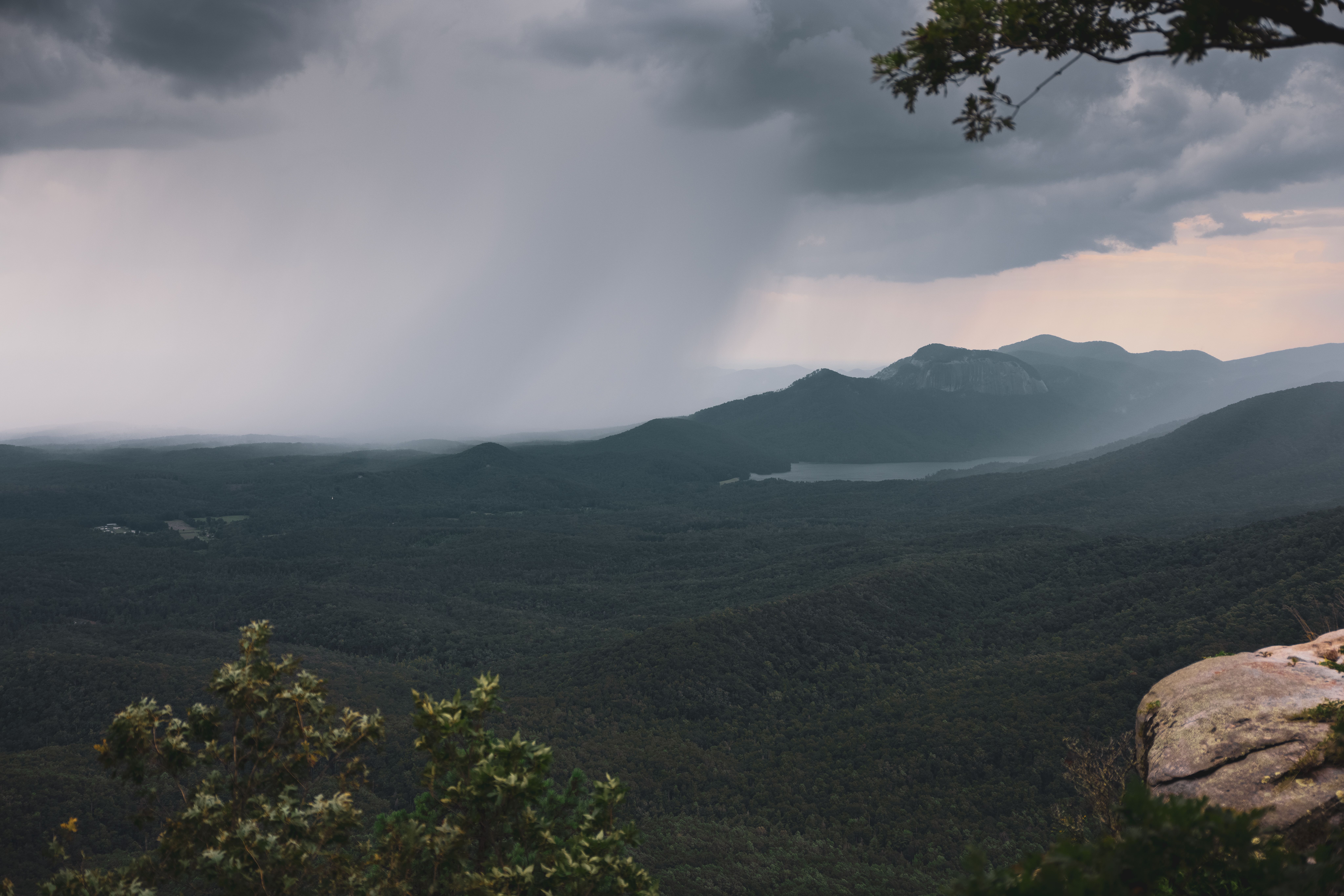 A rainstorm moving over forested mountains