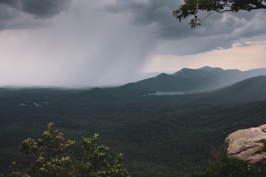 A captivating view of a rainstorm covering lush mountains and forests.