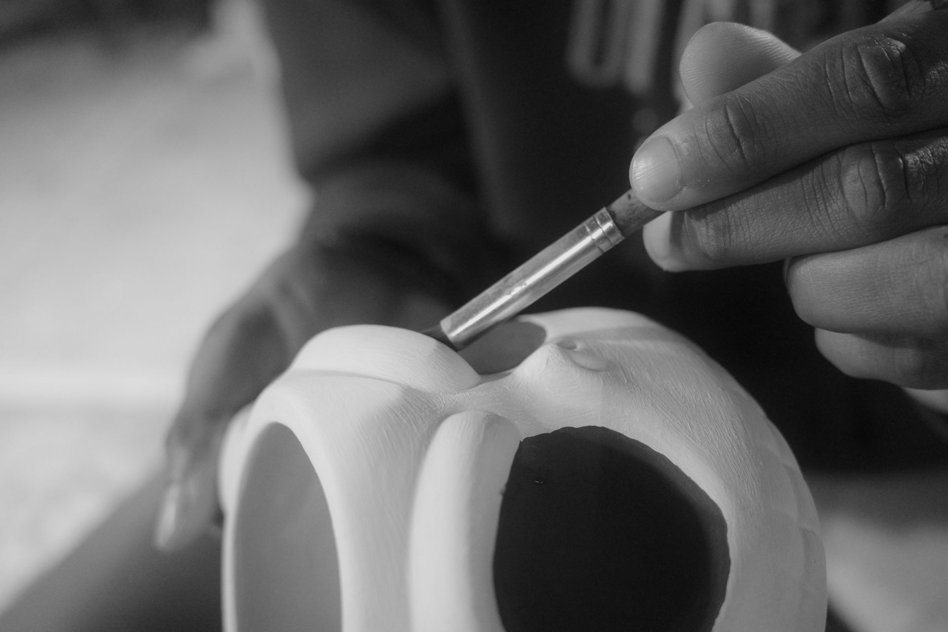 Close-up of an artisan's hand painting a ceramic skull with precision in Cancun.
