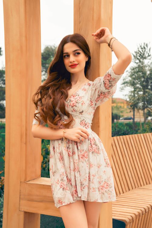 Free Stylish woman in a floral dress posing gracefully outdoors, showcasing fashion. Stock Photo